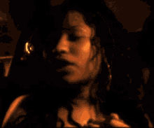 a close up of a woman 's face and hands in a dark room