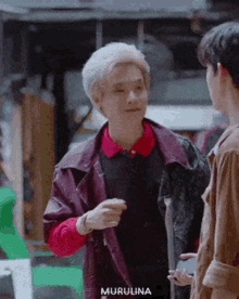 a man with gray hair is talking to another man .