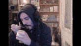 a man wearing headphones and a hooded jacket is eating something with a spoon
