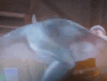 a blurred image of a person 's face with a blue shirt on