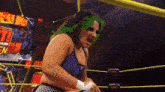 a female wrestler with green hair is screaming in a ring