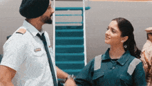 a man in a turban stands next to a woman in a uniform