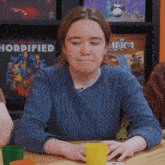 a woman sits at a table in front of a sign that says horrificed