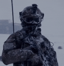 a soldier wearing a helmet and goggles is holding a gun in the snow