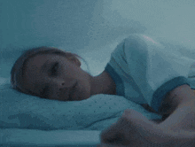 a woman with blonde hair is laying on a bed with a pink pillow