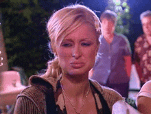 a woman with blonde hair and a ponytail is making a sad face