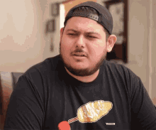 a man with a beard wears a black shirt with a corn on the cob on it