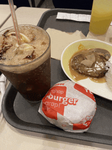 a hamburger and a drink on a tray with a wrapper that says ' hamburger ' on it