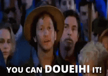 a man in a cowboy hat stands in front of a crowd and says you can doueihi it .