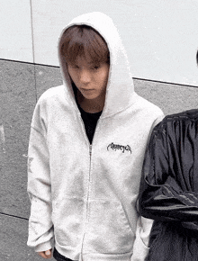 a person wearing a white hoodie with a black logo on it
