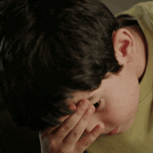 a close up of a person covering their face with their hands