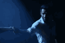 a man in a white shirt is holding a woman 's hand in a dark room