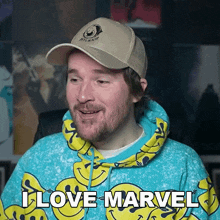a man wearing a hoodie with smiley faces and a hat that says i love marvel