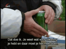 a person is opening a green soda can with sbs written on the bottom