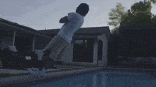 a man jumps into a pool in front of a house