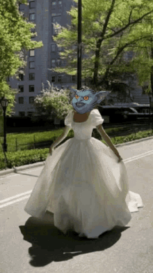 a woman in a white dress with a blue cat on her face