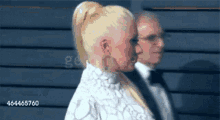 a woman with a ponytail is standing next to a man in a tuxedo .