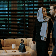 a woman with a scarf on her head stands next to a man