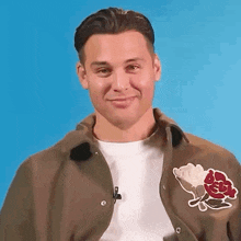 a man wearing a brown jacket with a red rose on the back is smiling .