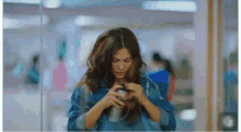 a woman in a denim jacket is holding a cup in her hands .