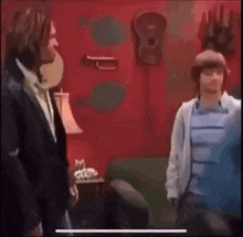 a man in a suit and a boy in a blue shirt are standing in a living room .
