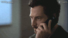 a man talking on a cell phone with wildcards written on the bottom right