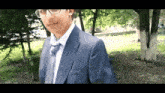 a man in a suit and tie is standing in the woods