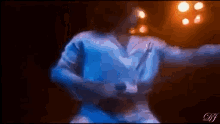 a man in a blue shirt is dancing on a stage in front of a microphone .