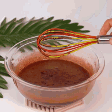 a person is holding a whisk over a bowl of chocolate sauce