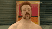 a shirtless man with a beard is standing in front of a sky sports live sign