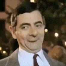 mr bean is wearing a suit and tie and is making a funny face .