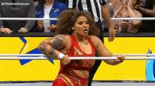 a woman in a red and gold outfit is standing in a wrestling ring holding a bar .