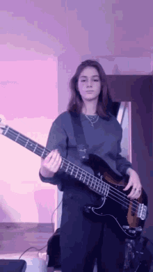 a girl is playing a bass guitar in front of a purple background