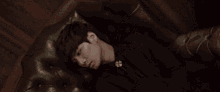 a young man is laying in a chair with his head on the armrest .