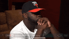 a man wearing a chicago bulls hat sits with his hands on his chin