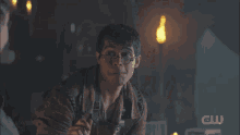 a man wearing glasses is making a funny face with the cw logo behind him