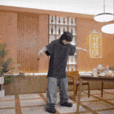 a man in a black shirt is dancing in a room with a sign on the wall that says kk