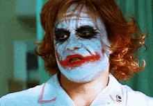 a man is wearing a nurse 's uniform and has a joker face painted on his face .