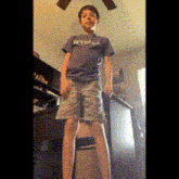 a young boy wearing a t-shirt that says mysha is standing on a chair .