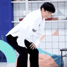a young man in a white shirt and black pants is kneeling down and smiling .