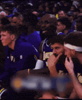 a basketball player wearing a lakers jersey is talking to another player