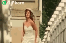 a bride in a wedding dress is walking down a sidewalk .