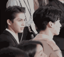 two men are sitting next to each other in a crowd and one of them is looking at the camera .