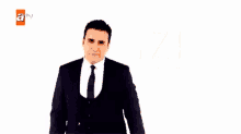 a man in a suit and tie is peeking out from behind a wall .
