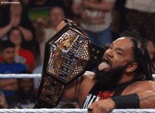 a man in a wrestling ring holding a championship belt that says champions