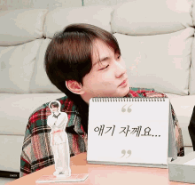 a young man sitting in front of a calendar with korean writing
