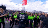 a man in a green and black jacket that says stake