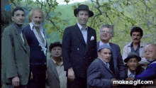 a group of men standing next to each other in suits and hats .