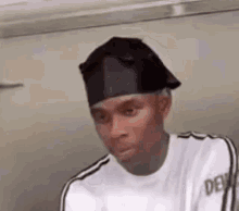 a man wearing a black headband and a white t-shirt is making a funny face .