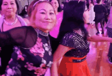 a group of women are dancing on a dance floor and one of them is wearing a floral top